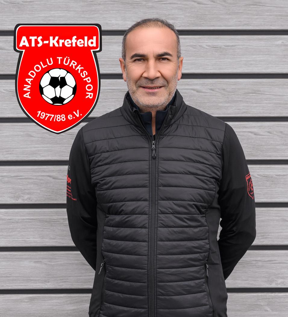 Mann mit kurzen Haaren und Jacke steht vor grauer Wand, das Logo von ATS Krefeld und Anadolu T&uuml;rksport ist im Bild.