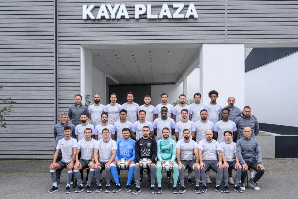 Gruppenfoto von Spielern und Trainern vor dem Geb&auml;ude KAYA PLAZA, angeordnet in mehreren Reihen.