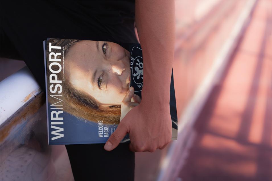 Hand einer Person h&auml;lt eine Zeitschrift mit dem Titel &bdquo;WIR IM SPORT&ldquo; und einem Portr&auml;t auf dem Cover.